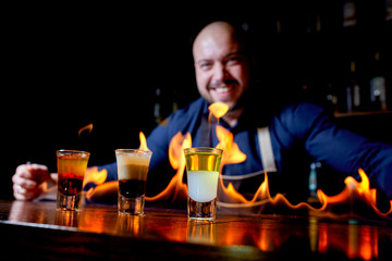 Fiery show at the bar. The bartender makes hot alcoholic cocktail and ignites bar. Bartender prepares a fiery cocktail. Fire on bar.