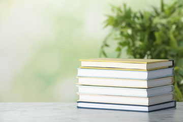 Stack of hardcover books on table against blurred background, space for text