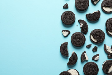 Tasty chocolate cookies with cream on color background, flat lay. Space for text
