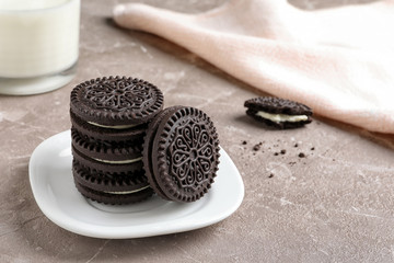 Plate with chocolate and cream cookies on table. Space for text
