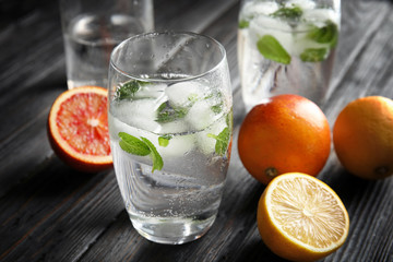 Glass of drink with ice cubes and fruits on wooden table