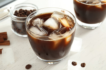 Glass of coffee drink with ice cubes on table
