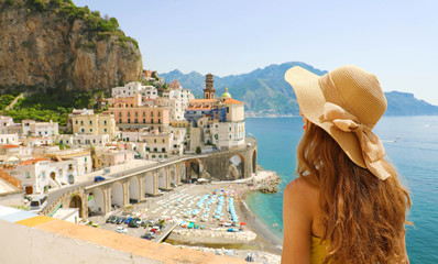 Summer holiday in Italy. Back view of young woman with straw hat and yellow dress with Atrani village on the background, Amalfi Coast, Italy - obrazy, fototapety, plakaty