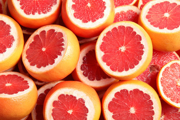 Many sliced fresh grapefruits as background, top view