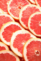 Many sliced fresh grapefruits as background, top view