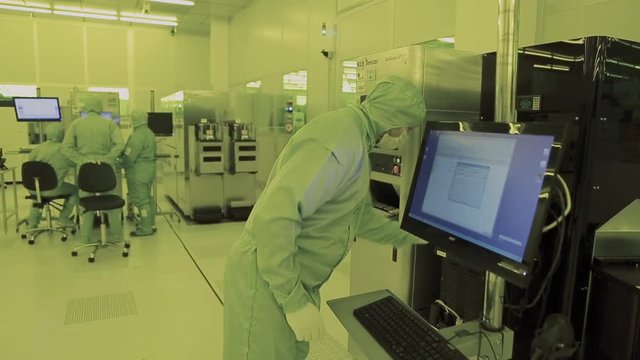 engineer scientist in sterile suits, mask. are in a clean zone looking at a process technologically advanced factory laboratory. Clean high tech environment with computer. microchip fabrication