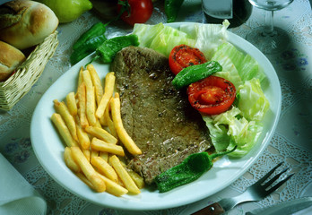 Plato con un bistec a la parrilla. patatas fritas y ensalada.