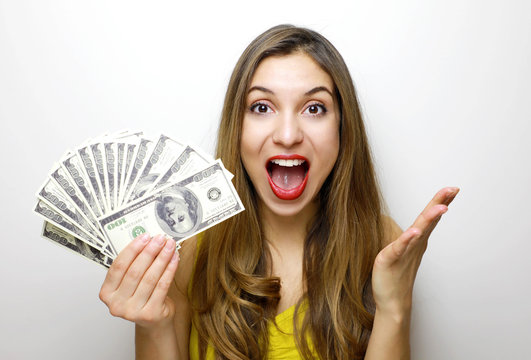 Portrait of excited pretty girl looking at camera with a bunch of money banknotes isolated over white background
