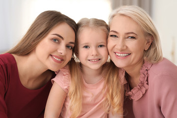 Portrait of young woman, her mature mother and daughter indoors