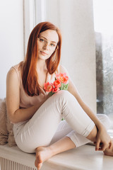 Pretty smiling joyfully female with fair hair, dressed casually, looking with satisfaction at camera, being happy. Studio shot of good-looking beautiful woman in sunny studio