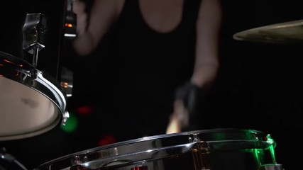 Girl drummer banging on a drum kit on stage.