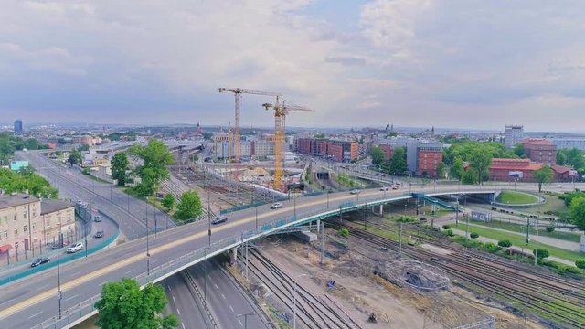 Panorama of Krakow city with a multi-level intersection, railroad tracks and cranes at the construction of a skyscraper. Aerial view from drone, from above