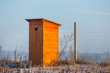 An old wooden toilet building at sunrise