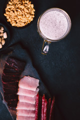beer and snacks. bar table. restaurant, pub, food concept. delicious craft unfiltered drink, salted nuts and meat appetizers set- ham, sausages and jerky. friday party atmosphere, brewery background