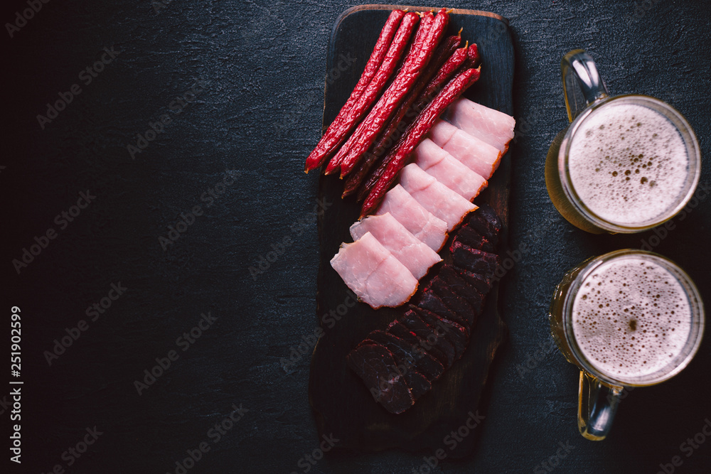 Wall mural beer and snacks. bar table. restaurant, pub, food concept. delicious craft unfiltered drink and meat appetizers set- ham, sausages and jerky. friday party atmosphere, brewery background