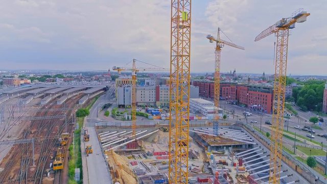 Construction cranes on a skyscraper construction site with city panorama in background. Aerial view from drone, from above