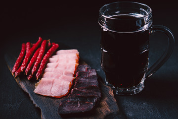 beer and snacks. bar table. restaurant, pub, food concept. delicious stout and meat appetizers set- ham, sausages and jerky. friday party atmosphere, brewery background