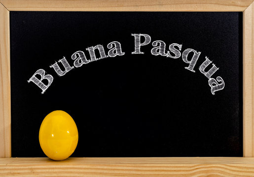 Easter frame with painted eggs and chalkboard. Happy Easter in white chalk. Happy Easter in italian : buana pasqua