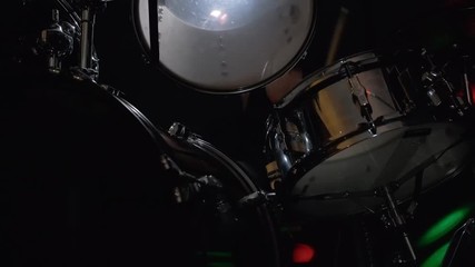 Girl drummer banging on a drum kit on stage.