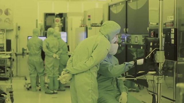 two engineer scientist in mask overalls sterile goes to the clean area. high-tech manufacturing nano technology. watching the production process