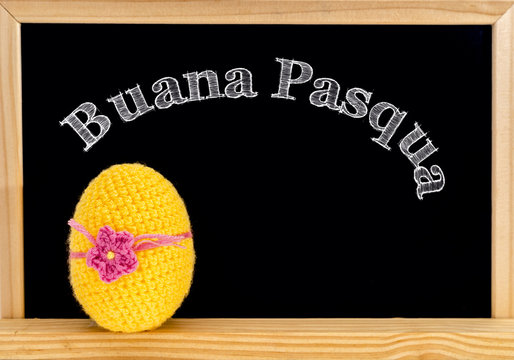 Easter frame with painted eggs and chalkboard. Happy Easter in white chalk. Happy Easter in italian : buana pasqua