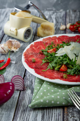 close-up carpaccio meat with arugula and slices of parmesan cheese
