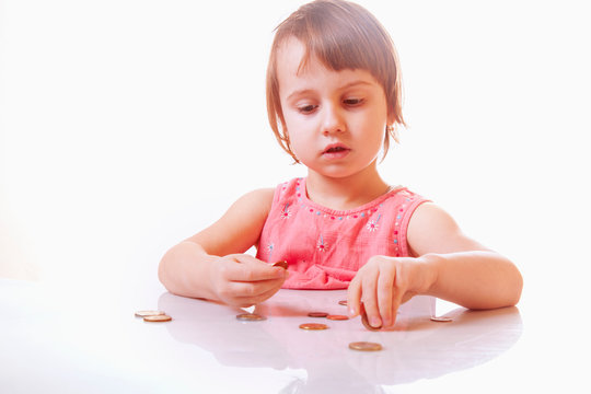 Little business child girl with coins planing the family budget. Emotions of facial expressions. Humorous picture.
