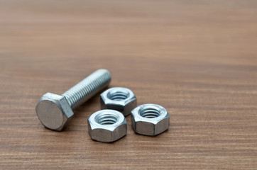 Metal fasteners, bolt and nuts for construction, close-up on a wooden background. Selective focus.