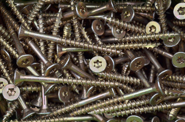 Metal fasteners. Many golden tapping screws for construction as an industrial style background,...