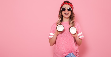 Portrait of a girl with coconuts, on a pink background