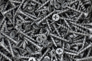 Metal fasteners. Many black tapping screws for construction as an industrial style background, close-up.