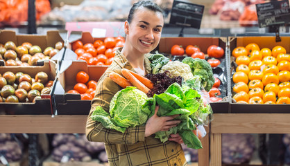 Woman in the supermarket. Beautiful young woman shopping in a supermarket and buying fresh organic vegetables