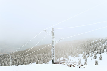 Old abandoned ski lift on a snow covered hill in winter texture graphics on a foggy day