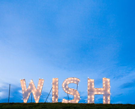 Illuminated lighted wish sign. Aspirations hope concepts background.