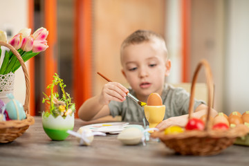 Cute little boy painting Easter eggs