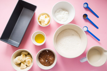 Visual guide made of single photo showing the different step to prepare a banana bread, ingredients to prepare the bread , eggs, flour, sugar, grreek yogurt, oi and butter, and banana,are displayed ov