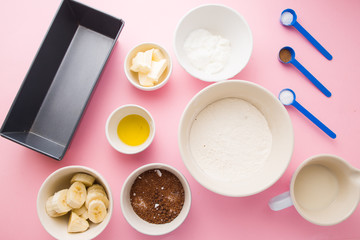 Visual guide made of single photo showing the different step to prepare a banana bread, ingredients to prepare the bread , eggs, flour, sugar, grreek yogurt, oi and butter, and banana,are displayed ov