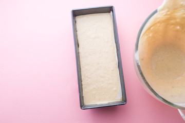 Visual guide made of single photo showing the different step to prepare a banana bread, add ripe bananas to the mixture of butter and sugar on a mixing bowl ,over a pink background, top view, follow t