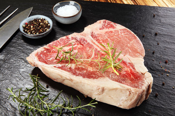 Raw T-bone steak on stone cutting board.