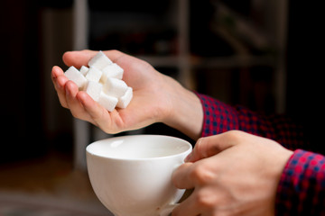young man adding sugar in the cup b