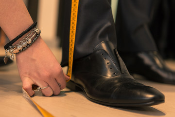 Detail of tailor's hands taking measurements for a man dress