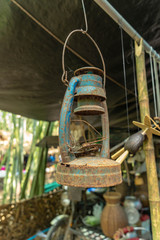 Old rusty gasoline lantern hanging on the metal bar.