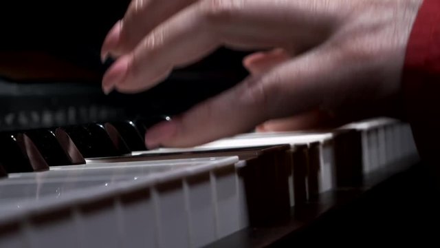 Man learning to play the piano with backlit keys. Close-up.
