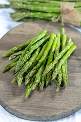 Fresh raw green asparagus vegetable on wooden plank, close up