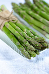 Fresh raw green asparagus vegetable on white board, close up