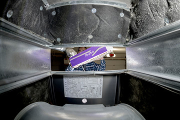 Man inserts a new filter into a home furnace from outside
