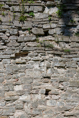 Stone wall texture. Weathered surface of the ancient fortress wall. Uneven rough cracked stonework. An old protective cross is visible in the masonry. Perfect for background and design.