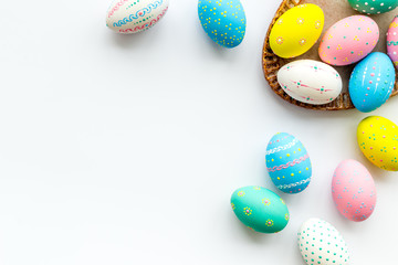 Easter traditions. Colorful Easter eggs in basket on white background top view copy space border