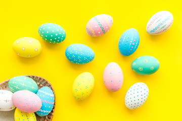 Easter traditions. Colorful Easter eggs in basket on yellow background top view