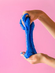 The child stretches slime blue on a pink background.